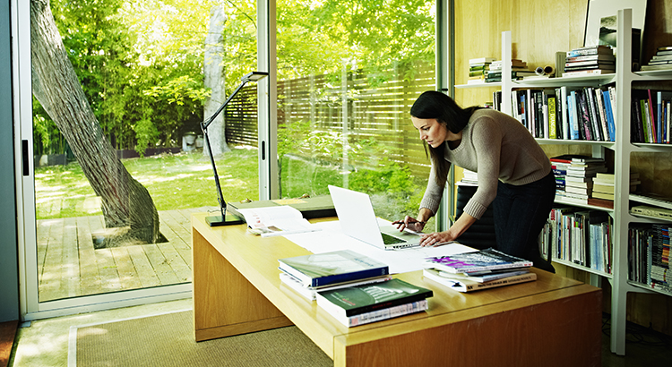 Woman working on laptop in office of contemporary home